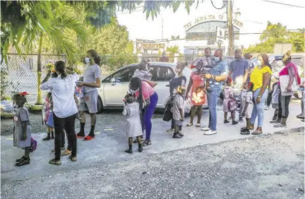  ??  ?? Parents arrive with their children at RJR Basic School in St Andrew yesterday morning.