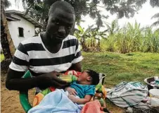  ?? Abbas Dulleh / Associated Press ?? James Harris, feeding his child outside his house in Monrovia, Liberia, said nurses were too afraid to touch his wife, Salome Karwah, even though she was immune to the Ebola virus.