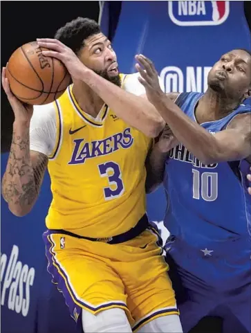  ?? Tony Gutierrez Associated Press ?? THE LAKERS’ Anthony Davis tries to drive against the Mavericks’ Dorian Finney-Smith. Davis played 17 minutes as the Lakers try to ease him back into the lineup after being sidelined since Feb. 14.