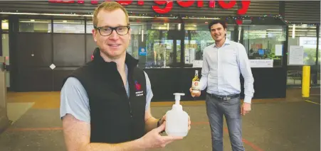  ?? ARLEN REDEKOP ?? Anesthesio­logist Neil Ramsay holds a bottle of donated hand sanitizer while Chris Nelson, owner of Pacific Sands resort in Tofino, holds a bottle of Shelter Point Artisanal Single Malt Whisky. Shelter Point distilled and delivered 2,000 litres of hand sanitizer to the hospital.