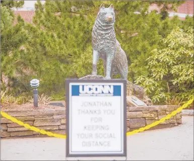  ?? MARK MIRKO/HARTFORD COURANT ?? A sign in front of the statue of Jonathan the Husky promotes social distancing. As much of the nation sees coronaviru­s cases on the rise, it is starting to seem inevitable that there will be little to no college sports this fall.