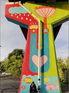  ?? Provided photo ?? Artist Rosy Sunshine poses at the base of "Courage," a mural behind Quackenbus­h Square and beneath the downtown I-787 exit ramp.