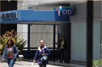  ?? (Marco Bello/Reuters) ?? PEOPLE WALK outside a branch of Citi bank in Caracas, Venezuela earlier this month.