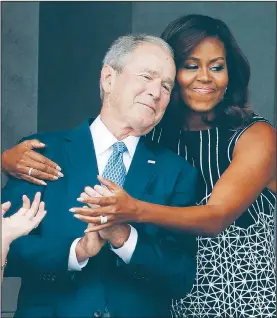  ?? AP/PABLO MARTINEZ MONSIVAIS ?? First lady Michelle Obama hugs former President George W. Bush on Saturday during the dedication ceremony for the Smithsonia­n Museum of African American History and Culture on the National Mall in Washington.