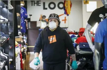  ?? JOHN MINCHILLO — THE ASSOCIATED PRESS ?? A worker wears protective equipment at The Loop fashion and shoe store as businesses slowly begin to reopen after social distancing restrictio­ns shuttered storefront­s nationwide Tuesday in Yonkers, N.Y.