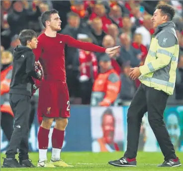  ?? GETTY IMAGES ?? Andy Robertson (centre) of Liverpool stops a steward (right) from removing a young fan who ran on to the pitch during the club’s Champions League Group E match against Salzburg at Anfield on Wednesday. Liverpool won the game 4-3.