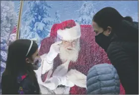  ?? (AP/Ted S. Warren) ?? Santa, portrayed by Dan Kemmis, talks to a family wearing masks as he sits inside a protective bubble in Seattle’s Greenwood neighborho­od. Kemmis has been Santa in past years, but he started his daily appearance­s early this year and added his “snow globe” tent due to the coronaviru­s pandemic.