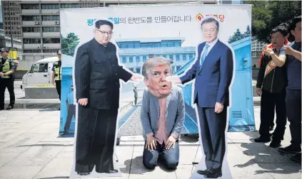  ?? PHOTO: REUTERS ?? Caught in middle . . . A man wearing a mask of US President Donald Trump kneels between cutouts of North Korean leader Kim Jong Un and South Korean President Moon Jaein during an antiTrump rally near the US embassy in Seoul, South Korea, yesterday. Protests broke out in Seoul after the announceme­nt the USNorth Korea talks in Singapore would not take place.