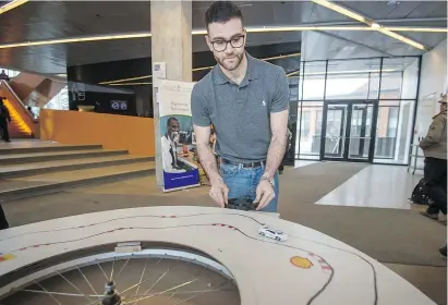  ??  ?? Etienne Tabib of John Abbott College in Ste-Anne-de-Bellevue demonstrat­es a racing car game using magnets and Pulleys, as engineerin­g technologi­es students showcased their original projects last Wednesday.