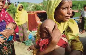  ?? [ FOTO EPAEFE ] ?? Wanita pelarian Rohingya memegang bayinya ketika menunggu penyerahan bantuan di Palongkhal­i Bazar, Ukhiya, Bangladesh.