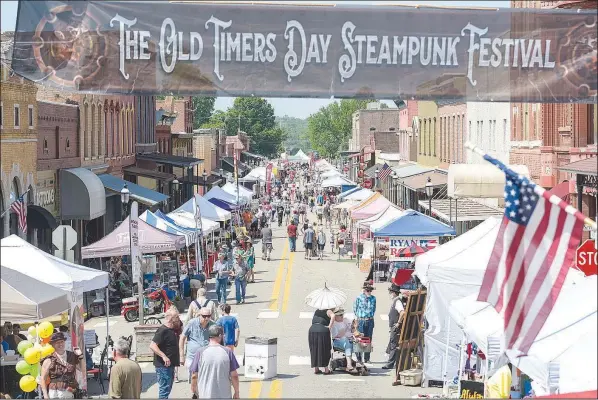  ?? (File Photo/ NWA Democrat-Gazette/Hank Layton) ?? Attendees walk under a banner on May 15, 2022, at the 44th annual Old Timers Day Steampunk Festival along historic Main Street in downtown Van Buren. The two-day free event organized by the Old Town Merchants Associatio­n featured costumed characters and six blocks’ worth of retrofutur­istic-themed entertainm­ent and vendors offering arts, crafts, jewelry and clothing, as well as food.