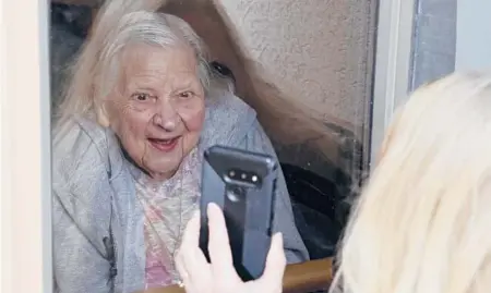  ?? JEFFREY T. BARNES/AP ?? Laura Corridi shows a photo to her mother, Emma Sahl, 93, on March 6 at Northgate Health Care Facility in North Tonawanda, New York.