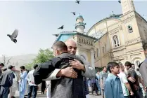  ??  ?? Afghan Muslims hug each other after prayers, in Kabul. Afghans welcomed the start of the Taliban's ceasefire as they celebrated Eid al-Fitr. AFP