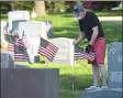  ?? PETE BANNAN - MEDIANEWS GROUP ?? John Bergin of Secane places a flag on his uncle John Bergin’s grave at Arlington Cemetery. His uncle was a Navy veteran of World War II.