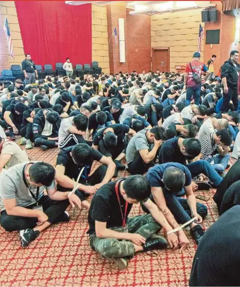  ?? PIC BY LUQMAN HAKIM ZUBIR ?? Scammers from China being held at the Immigratio­n Department headquarte­rs in Putrajaya on Thursday following a recent raid on a investment and foreign exchange scam syndicate in Cyberjaya.