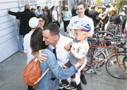  ?? Paul Chinn / The Chronicle ?? Bob Linder, holding son Felix, hugs a supporter as a crowd protests his firing as curator of the museum at 500 Capp St.