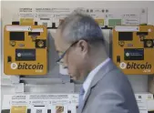  ??  ?? A man next to Bitcoin ATMs in Hong Kong, 21 December 2017