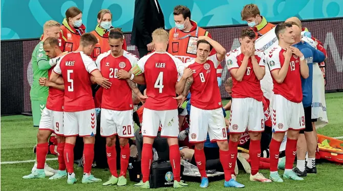  ?? AP ?? Distraught Danish players and medical staff surround team-mate Christian Eriksen after he collapsed on the pitch during the Euro 2020 match against Finland. Eriksen was later reported to be awake and in a stable condition in hospital.