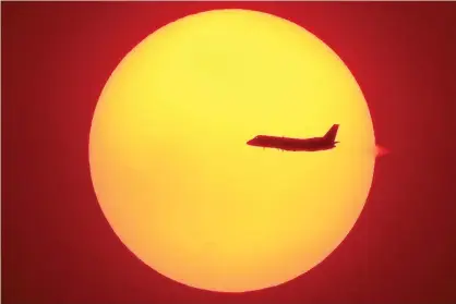  ?? Photograph: AFP via Getty Images ?? An aircraft flying across the setting sun in Sydney, as smoke haze continued to hang over the city from bushfires that have swept Australia. Photo taken on 4 December 2019.