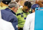  ?? Elaine Thompson / Associated Press ?? Seahawks QB Russell Wilson has his hand examined after an injury in Thursday’s 26-17 loss to the Rams.