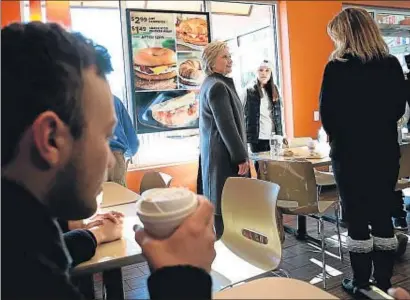  ?? JUSTIN SULLIVAN / AFP ?? Hillary Clinton saludando a los propietari­os de Dunkin Donuts en Manchester, Nuevo Hampshire