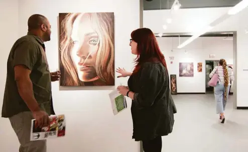  ?? Christian Abraham / Hearst Connecticu­t Media ?? Cristyn Martino and her friend Sebastian Morrell check out a piece of artwork by Liz Squillace during the 10th annual Bridgeport Art Trail Downtown Kick-off and Artists' Party at Read's ArtSpace in Bridgeport in 2018.