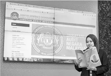  ??  ?? A-G’s Department personnel, Siti Zulaiha Mustapar reading the Auditor-General’s Report 2016 Series 1 at the Parliament building in Kuala Lumpur yesterday. — Bernama photo