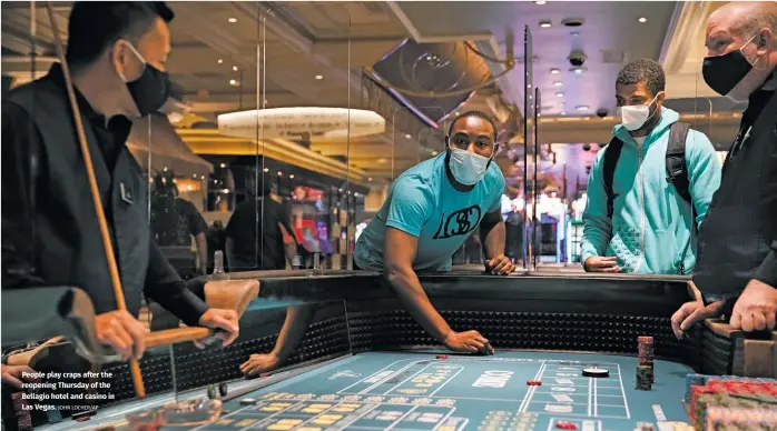  ?? JOHN LOCHER/AP ?? People play craps after the reopening Thursday of the Bellagio hotel and casino in Las Vegas.