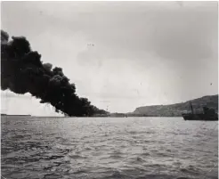  ?? ?? ■ Above left and right: HMS Foylebank ablaze and sinking in Portland Harbour. In the image of the ship listing, a tender can be seen removing Mantle and other casualties ashore. Portland Heights rises beyond and is the location where Jack Mantle VC lies buried.