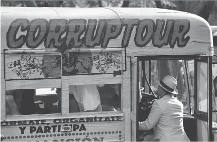  ?? YURI CORTEZ/AFP/GETTY IMAGES ?? A man prepares to emark on the “Corruptour,” a bus that offers a sightseein­g tour through different points, institutio­ns and companies in Mexico City related to alleged scandals and corruption in recent Mexican history.