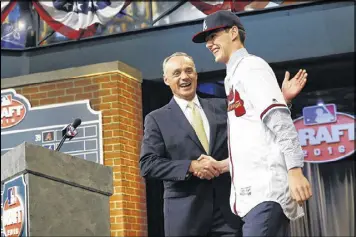  ?? JULIO CORTEZ / AP ?? A year ago, Commission­er Rob Manfred shook hands with Ian Anderson, a high school pitcher from Clifton Park, N.Y., after Anderson was picked by the Braves.