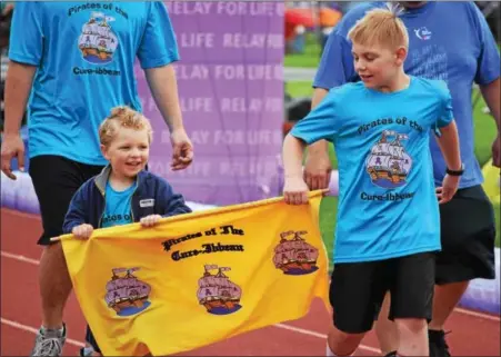  ?? MARIAN DENNIS — DIGITAL FIRST MEDIA ?? Two young relay participan­ts make their way down the track with a banner for their team. The purpose of the event is to have at least one member on the track at all times for a 24-hour duration to symbolize that cancer never sleeps.