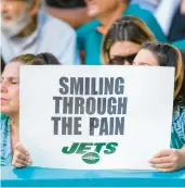  ?? DOUG MURRAY/AP ?? A Jets fan holds a sign reading “Smiling through the pain” during a game against the Dolphins on Jan. 8 in Miami Gardens, Fla.