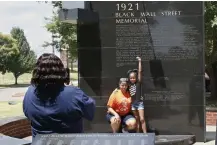  ?? Sue Ogrocki, The Associated Press ?? Katrina Cotton, center, of Houston, poses for a photo with her daughter, Kennedy Cotton, 7, as her aunt, Janet Wilson, left, takes the photo at the Black Wall Street memorial Monday in Tulsa, Okla.