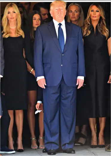  ?? ?? Solemn: Donald Trump is flanked by his daughter Ivanka, left, and wife Melania, right