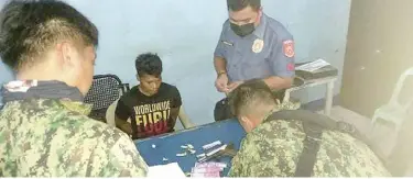  ?? ROMEO MARANTAL ?? Jerwin Cortes Laguna, 25, is held for questionin­g following his arrest Saturday night at a checkpoint in the mountain barangay of Lusaran, Cebu City for illegal possession of firearms. Several sample ballots, two of which have money attached, were also found in his possession.