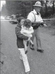  ?? AP/TED S. WARREN ?? Ryan Spurling (right), of the Mason County, Wash., sheriff’s office, escorts Adeline Peebles and a child away from the scene of a fatal shooting Friday near Belfair.