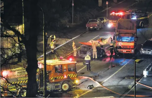  ?? PHOTO: STEPHEN JAQUIERY ?? Working together . . . Firefighte­rs assist at the scene of a double fatality crash between a car and a truck near a sharp bend in King Edward St, Dunedin, early on Saturday.