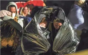  ?? GREGORY BULL/AP FILE ?? Two women from Cuba try to keep warm after crossing the border from Mexico and surrenderi­ng to authoritie­s to apply for asylum near Yuma, Arizona. An undergroun­d market has emerged for migrants seeking U.S. sponsors since the Biden administra­tion announced that it would accept a limited number of people from Venezuela, Cuba, Nicaragua and Haiti.