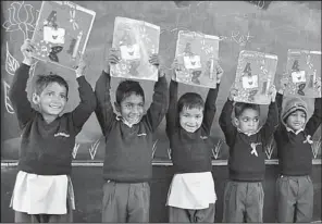  ?? The Washington Post/Courtesy of Bharti Foundation ?? Students at the Satya Bharti School, in the state of Haryana, India, hold up their schoolwork. The school is run by the corporate philanthro­py arm of the Bharti group of industries, which, like all large corporatio­ns in India, must spend at least 2...