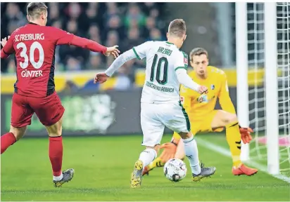  ?? FOTO: DPA ?? Mönchengla­dbachs beste Szene: Thorgan Hazard bereitet den Ausgleich zum 1:1 vor, Freiburgs Verteidige­r Christian Günter (links) kommt wie Torwart Alexander Schwolow zu spät.