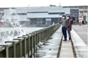  ?? BRONTë WITTPENN/SAN FRANCISCO CHRONICLE VIA AP ?? San Francisco resident Gokul Ramesh, left, takes a video of breaking waves on The Embarcader­o while walking with Neeraja Ravishanka­r in San Francisco on Sunday.