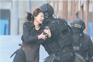  ??  ?? Jieun Bae runs to armed tactical response police officers for safety after she escaped from a cafe under siege at Martin Place in the central business district of Sydney on Dec 15, 2014.