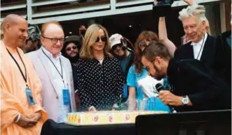  ?? — AFP ?? Recording artist Ringo Starr blows candles as his wife Barbara Bach (3rd L) and director David Lynch, friends and family look on during Ringo Starr's birthday celebratio­n at Capitol Records in Hollywood, California.