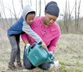  ?? STAFF PHOTO BY MARK PACE ?? Ansari Abdullah, 4, helps his mom, Khadijah Muhammad, water a tree Saturday at Lula Lake Land Trust. Tennessee residents planted about 250,000 trees.