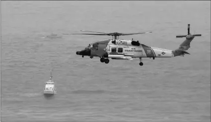  ?? AP PHOTO/DENIS POROY ?? A U.S. Coast Guard helicopter flies over boats searching the area where a boat capsized just off the San Diego coast on Sunday in San Diego.