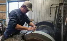  ?? ?? Yauji sharpens a freshly forged “santoku” knife at the Takefu Knife Village.