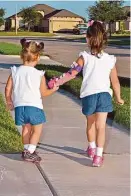  ?? Family photo ?? After receiving her prosthetic hand last month — in her chosen colors of pink and purple — 5-year-old Katelyn Vincik right, took a stroll with her younger sister Lacey, 3.