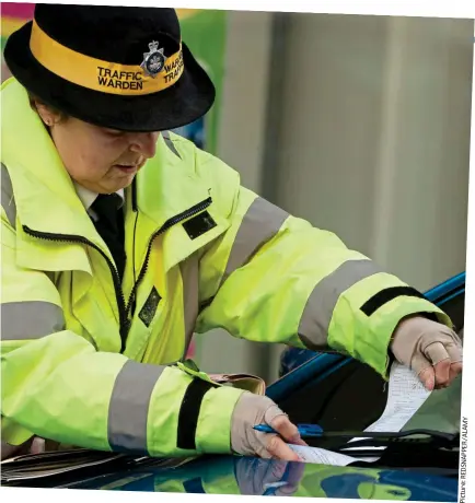  ??  ?? Frustratin­g: A parking warden hands out a penalty ticket