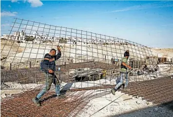  ?? MAHMOUD ILLEAN/AP ?? Workers carry constructi­on material at the settlement of Maaleh Adumin in January.